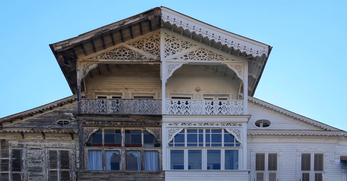 A detailed view of a half-renovated wooden house facade, showing old vs new.